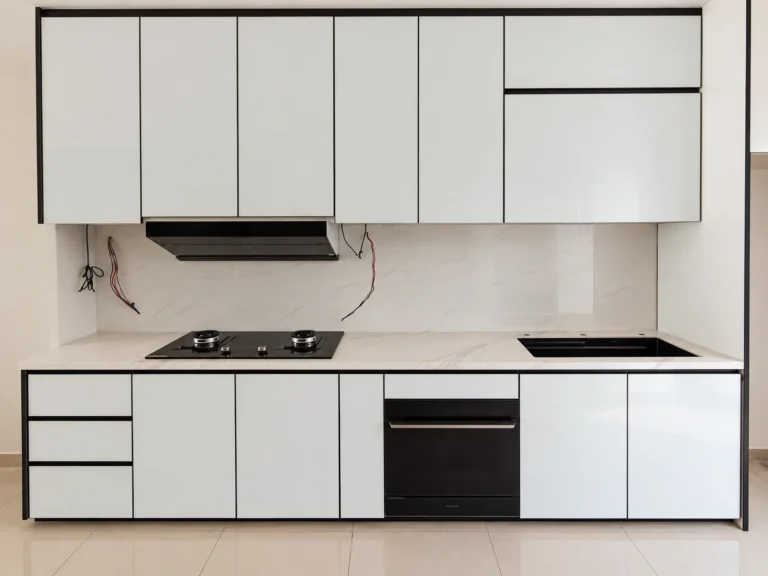 Front View Of White Kitchen Cabinets With Black Trim, Hob And Built-In Oven.